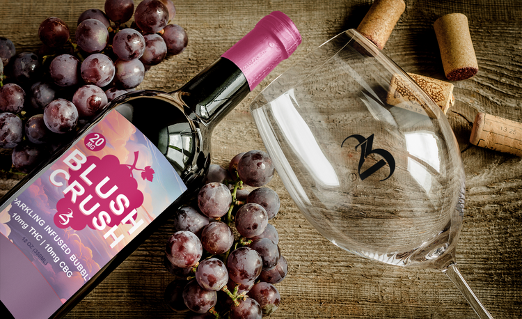 Wine bottle labeled 'Blush Crush' with a wine glass, grapes, and corks on a wooden surface.