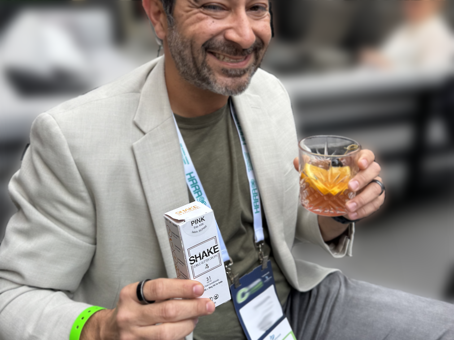 Man holding a box of PINK SHAKE and a glass with a drink, outdoors.