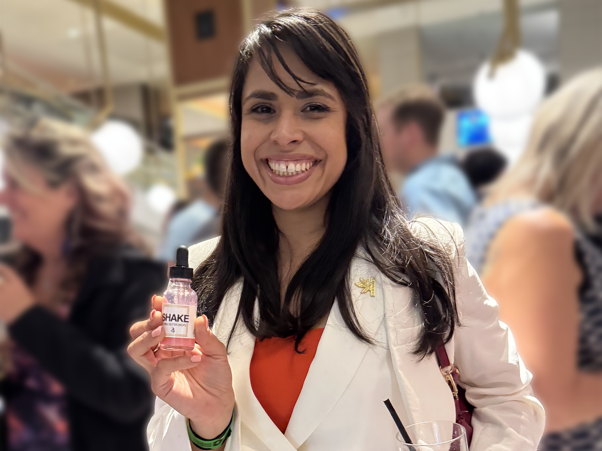 Woman holding a SHAKE bottle in a busy indoor setting.