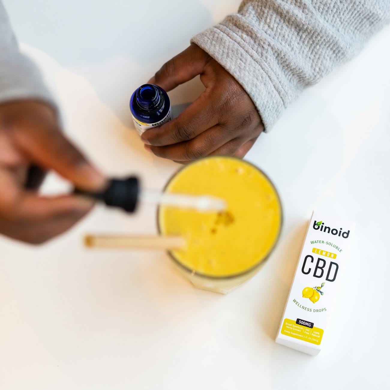 Dropper adding liquid into a glass drink, illustrating THC beverage enhancer use