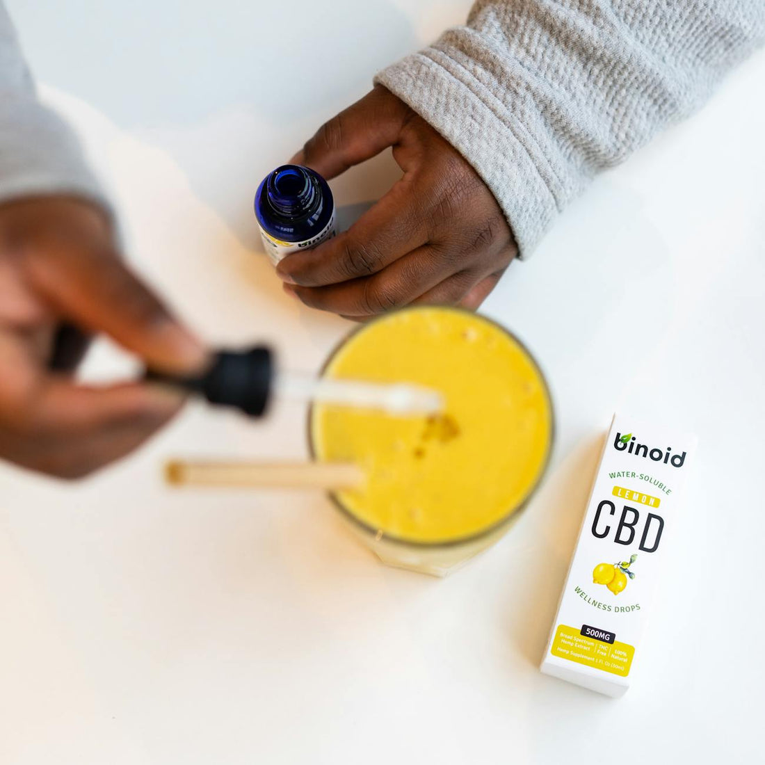 Dropper adding liquid into a glass drink, illustrating THC beverage enhancer use