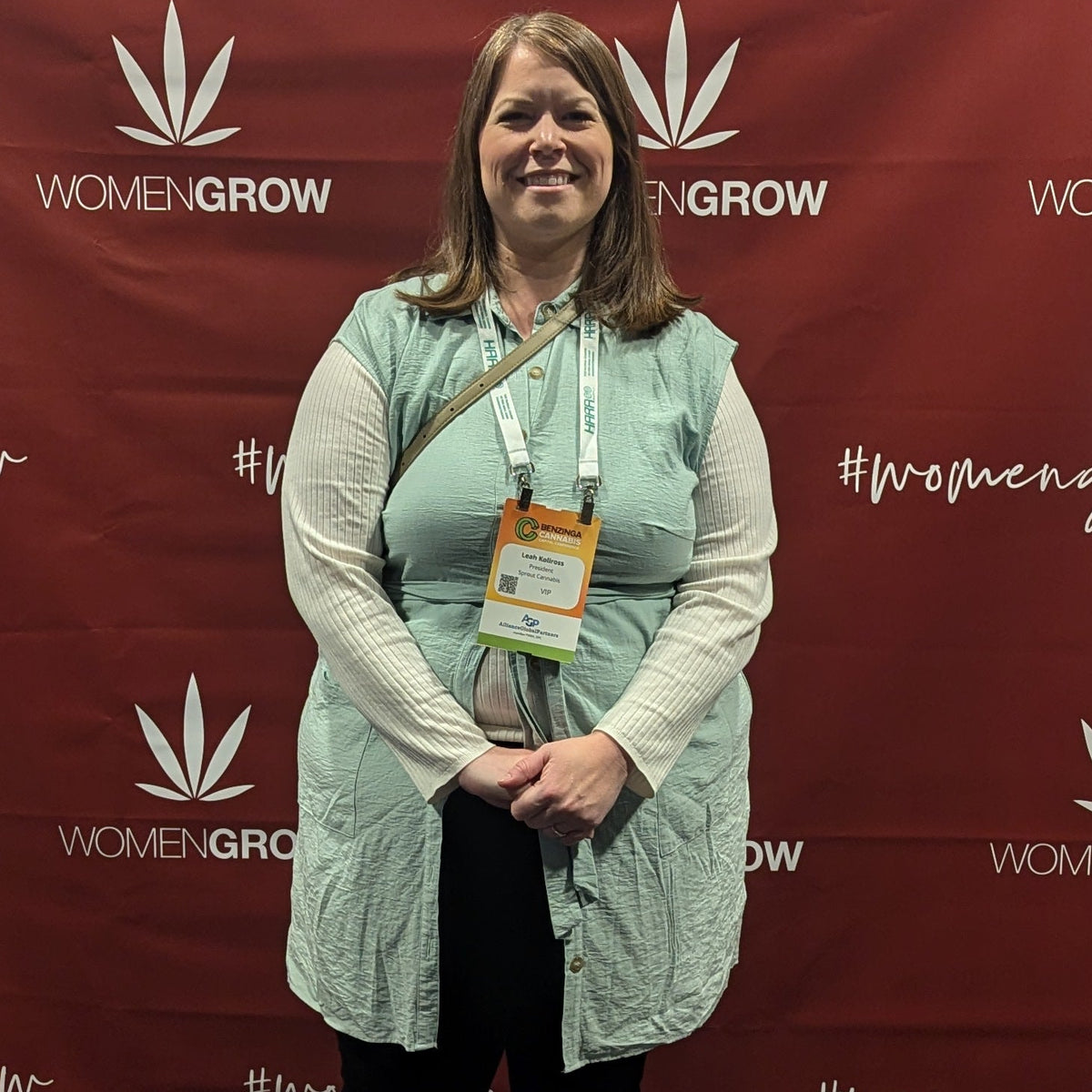 Woman standing in front of a 'WOMEN GROW' branded backdrop at an event.
