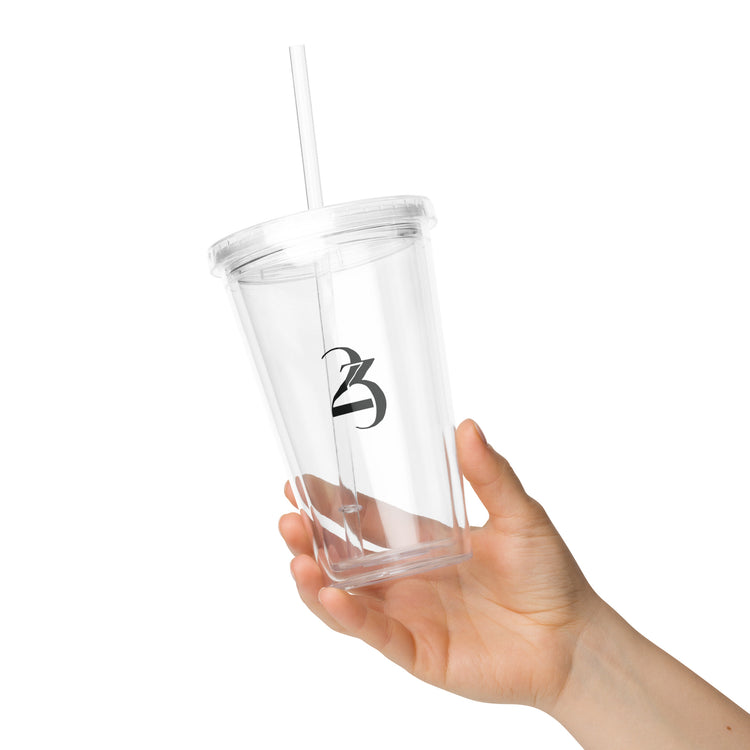 Clear tumbler with straw held by a hand on a white background